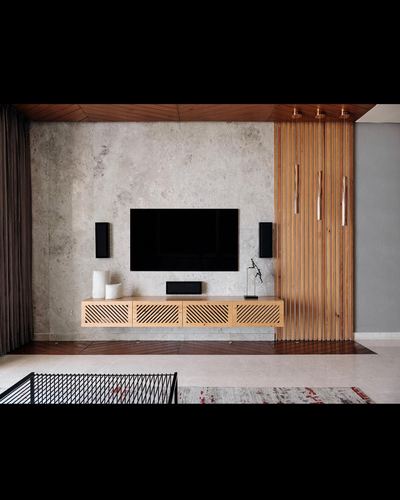TV media wall with textured stone backdrop and fluted wood partition with brass pendants