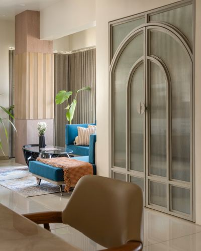 Living room with teal velvet sofa, glass table, and arched fluted glass door