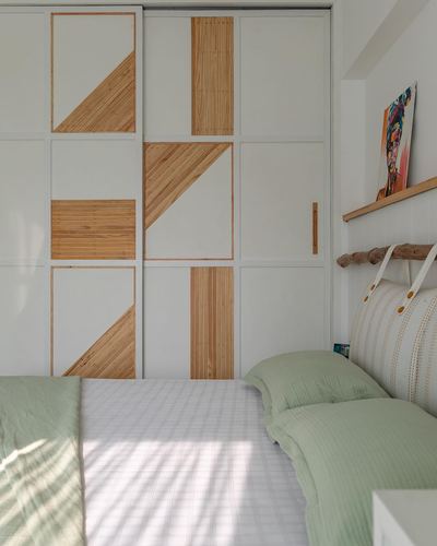 Bedroom with geometric wood-inlaid white wardrobe and green striped bedding