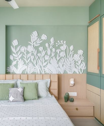 Sage green bedroom with sculpted white floral wall relief above a wood headboard