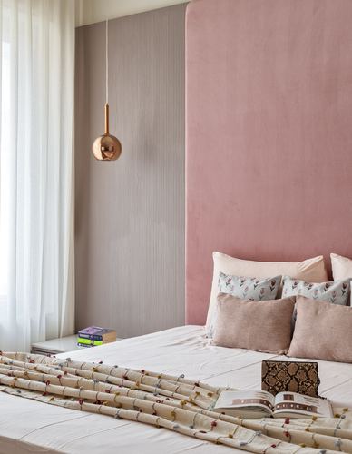 Bedroom with pink velvet headboard, fluted taupe panel, and copper pendant light beside bed