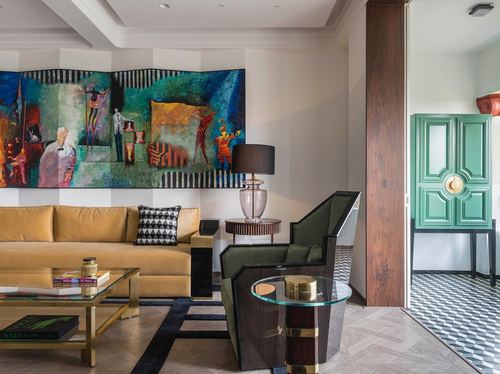 Art deco living room with mustard velvet sofa, green armchair, brass table and colorful mural