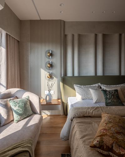 Bedroom with olive upholstered headboard, fluted panelling, and sunlight falling across wood floor