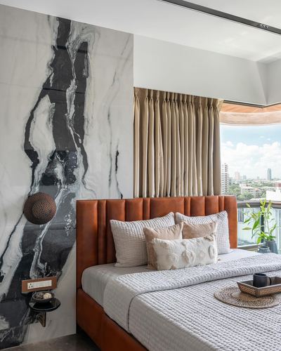 Bedroom with tan leather channel headboard against dramatic black-and-white marble wall and city view window