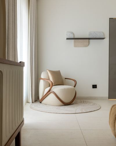 Cream bentwood armchair with round rug beneath a floating marble-topped wall shelf