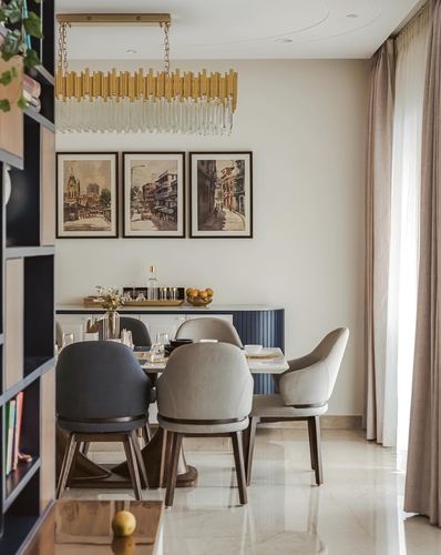 Dining room with marble table, mixed chairs, fluted navy sideboard, framed street art, brass chandelier