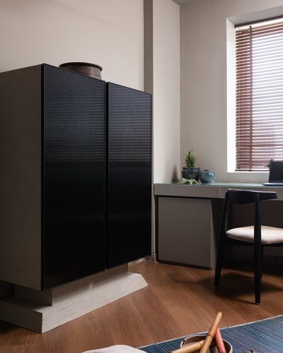 Study corner with fluted black cabinet on stone base beside desk and wooden blinds