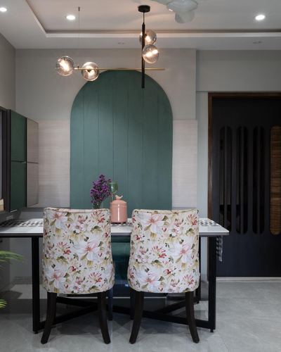 Dining nook with arched green paneled wall, sputnik chandelier, and floral upholstered chairs