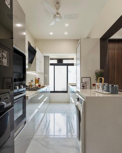 Glossy white galley kitchen with marble-look floor, black accents, and a window at the far end