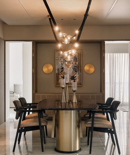 Dining room with oval table on brass pedestal beneath a bubble chandelier and framed artwork