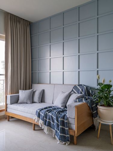Grey sofa with striped throw against a blue paneled wall, plant beside window