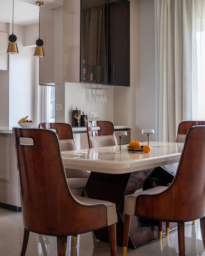 Dining table with marble top, wood-veneer chairs, and brass-topped pendant lights
