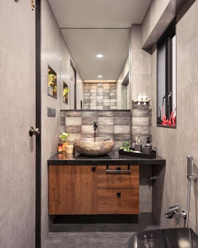 Compact bathroom with stone vessel sink, wood vanity, and patterned tile backsplash under large mirror