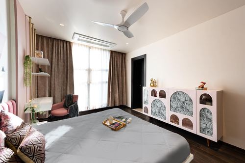 Bedroom with patterned arched cabinet, dark wood floor and sheer curtained window with soft daylight