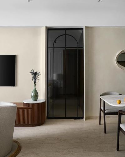 Neutral living room with arched black glass door, fluted wood console, and marble dining table