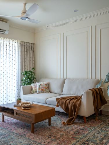 Beige panelled living room with cream sofa, rust throw, wood coffee table and patterned rug