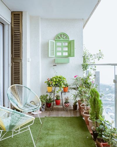 Balcony with acapulco chairs, tiered plant stand, and decorative green shutter mirror on wall