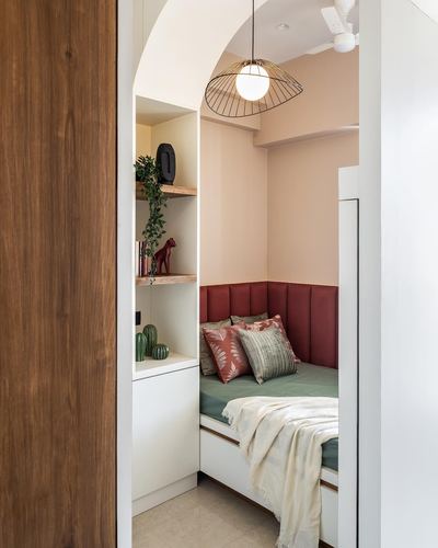 Arched bedroom nook with terracotta channel-tufted headboard, green bedding, and a woven pendant light over a built-in daybed.