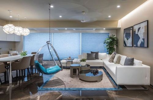 Living room with hanging bubble chair, white sectional, and blue window shades over bronze marble floor