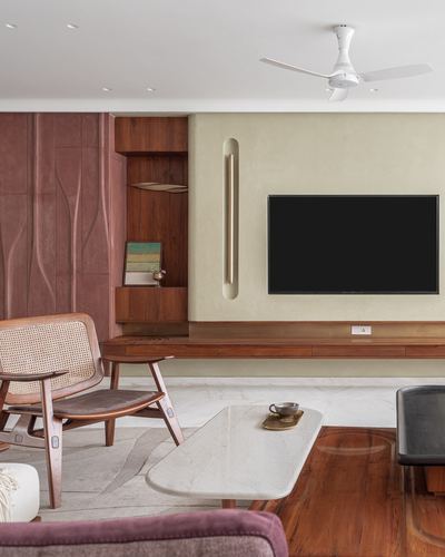 living room with cane armchair, marble coffee table and tv against textured terracotta wall panel