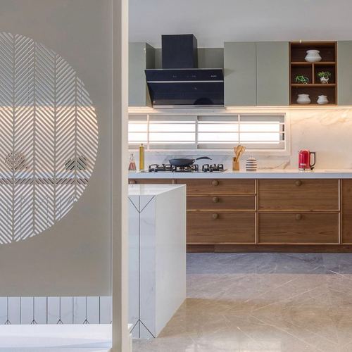 Kitchen island with jaali partition, sage cabinets, wooden drawers and black chimney hood