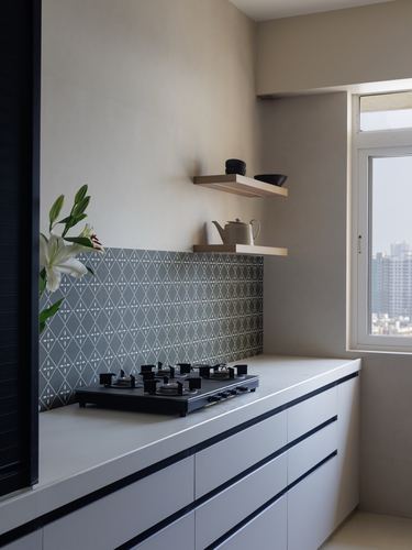 Minimalist kitchen corner with patterned tile backsplash, gas hob, and floating wood shelves near a window