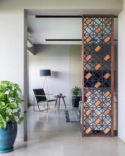 Foyer with wood-framed geometric screen dividing entrance from a minimal living room