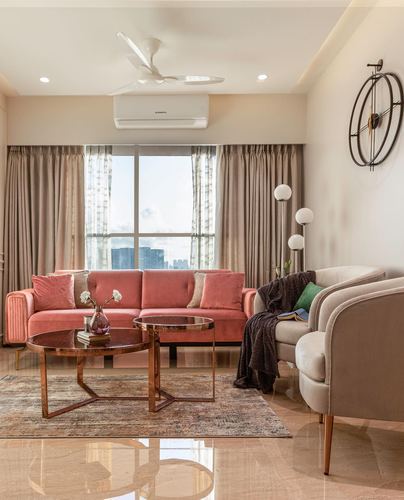 Living room with pink velvet sofa, glass coffee tables, and city view through curtained window
