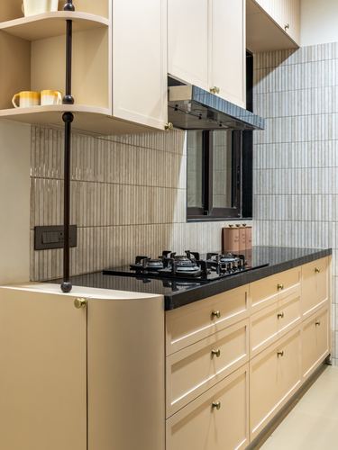 Beige kitchen island with black countertop, gas hob, and ribbed tile backsplash