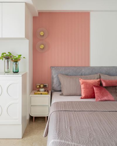 Bedroom with coral fluted wall panel, grey leather headboard, and pink velvet pillows