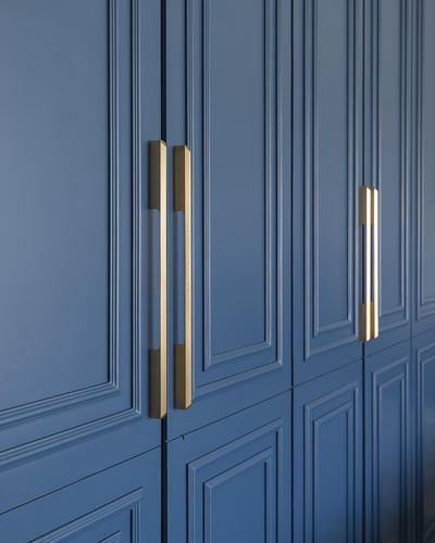 Close-up of blue panelled wardrobe doors with long vertical brass handles.