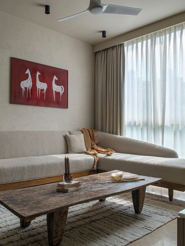 Beige boucle sectional sofa with wooden coffee table and red tribal-motif painting in living room