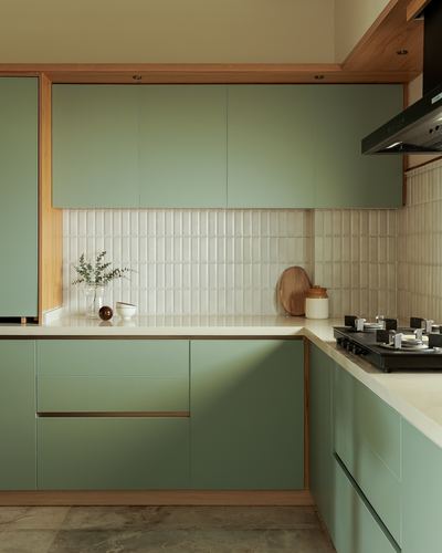 L-shaped sage green kitchen with wood trim, ribbed cream backsplash tile, and stone countertop