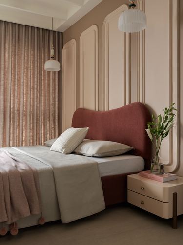 Bedroom with curved burgundy headboard, arched pink moulded wall panels and two pendant lights