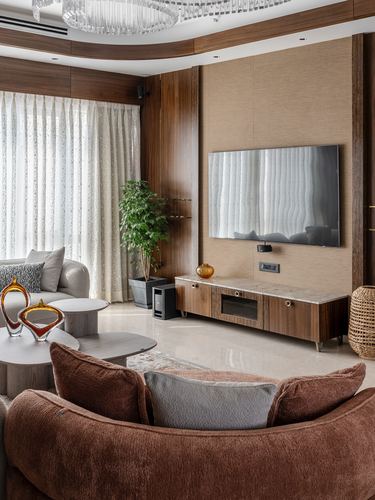 Living room with curved wood TV wall, marble console, brown sofa and sheer curtains