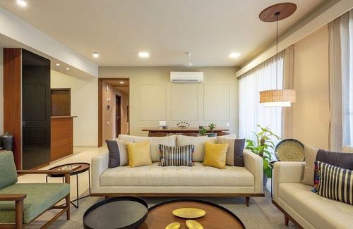 Beige living room with cream sofas, mustard cushions, round wood coffee tables and a woven pendant light