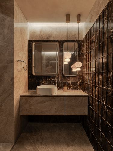 Bathroom corner with marble vanity, round vessel sink, twin mirrors and pendant lights beside a dark tiled wall