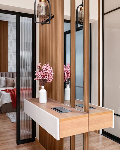 Foyer with floating wood and white console, fluted wood panels, mirror, pink flowers in vase