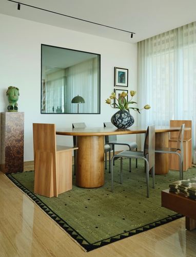 Dining room with oval wood table, drum bases, mixed chairs, mirror, and sheer curtains