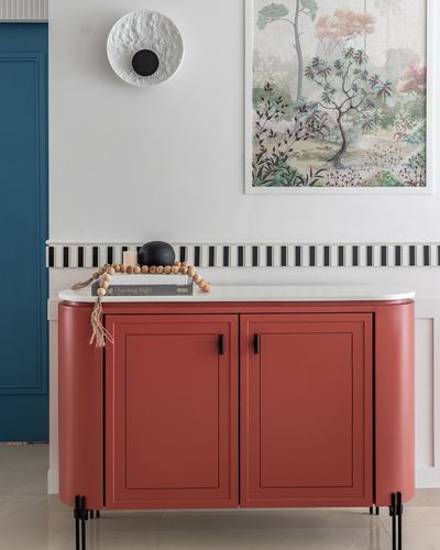 Terracotta curved sideboard with stone top beneath framed botanical print and textured wall sconce