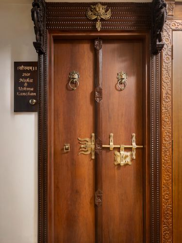 Carved wooden entrance door with brass lion-head knockers and traditional bolt, Mumbai apartment