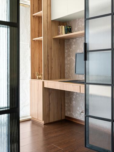 Wooden study nook with floating shelf, desk and monitor, seen through a reeded glass sliding door