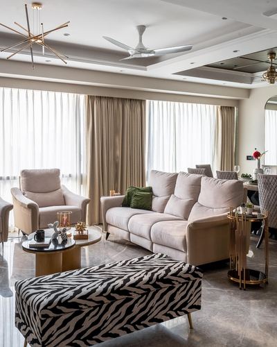 Art deco living room with beige sofa, zebra print bench, marble floor and brass accents