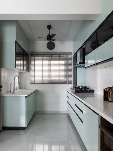 Galley kitchen with mint green glossy cabinets, white stone counters, and black-framed glass wall units