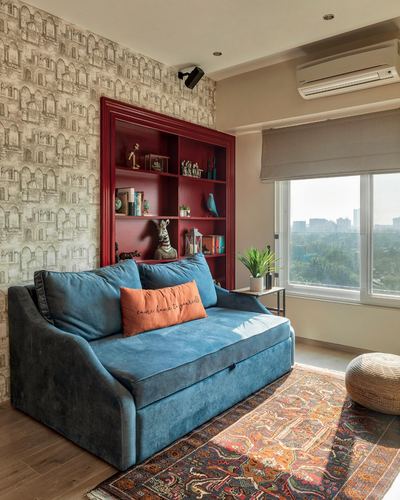 Blue velvet sofa in front of a red built-in bookshelf with a city-view window