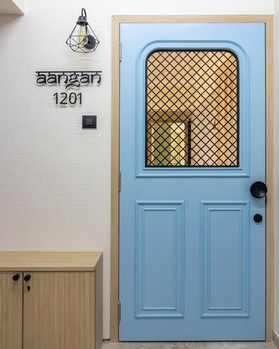 Pastel blue paneled entry door with arched grid glass window beside a white brick-textured wall with signage