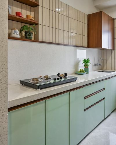 Galley kitchen with sage green cabinets, cream vertical tile backsplash, and wood-trimmed open shelving