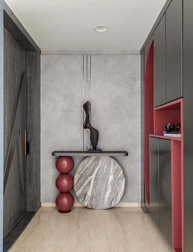 Entryway with red sphere-legged console, bronze sculpture, and marble disc against grey wall