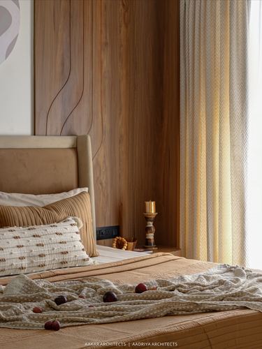 Bedroom corner with wood-panelled wall, beige upholstered bed and patterned curtains in warm light