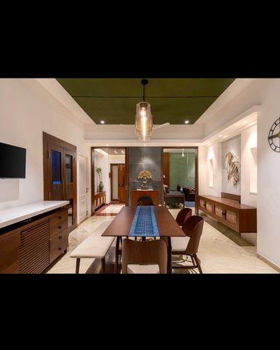 Dining room with wooden table, bench, chairs, pendant light, and green ceiling recess leading to living area beyond